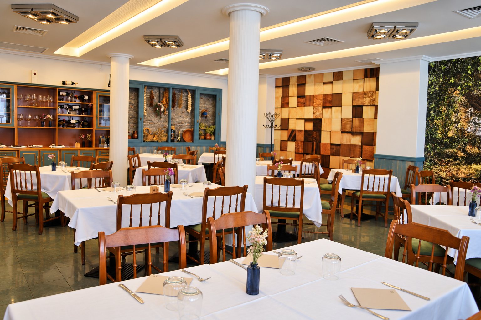 Comedor principal de La Palmera con mesas de mantel blanco, columnas blancas y la pared de tacos de madera al fondo.