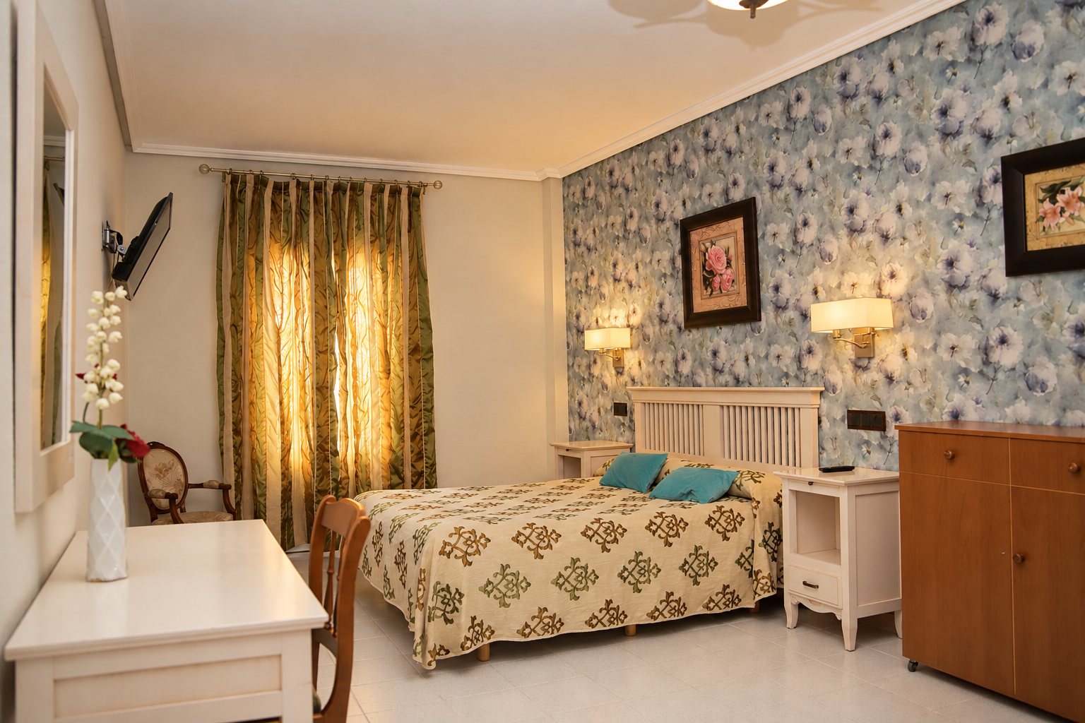 Habitación doble con papel pintado floral azul, cama con colcha estampada y mesillas blancas.